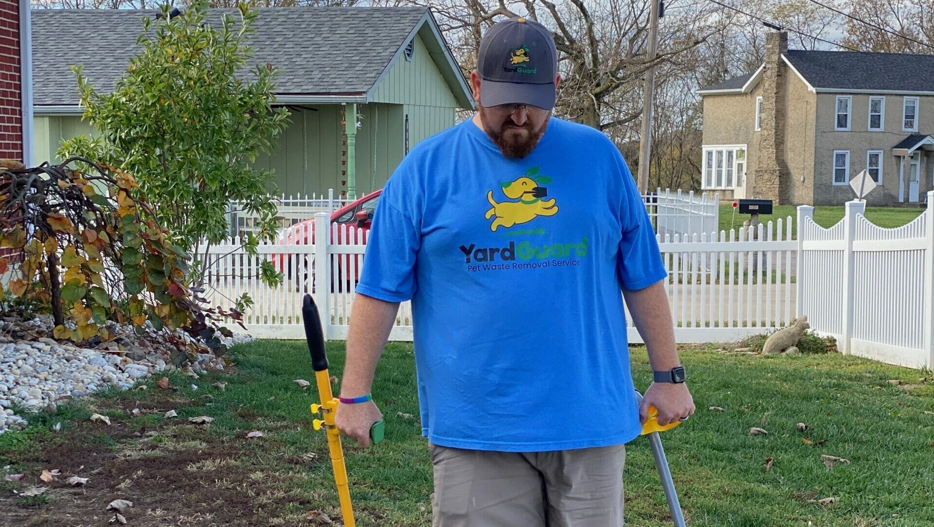 Yard Guard LLC employee in blue branded shirt performing dog waste removal in a residential yard