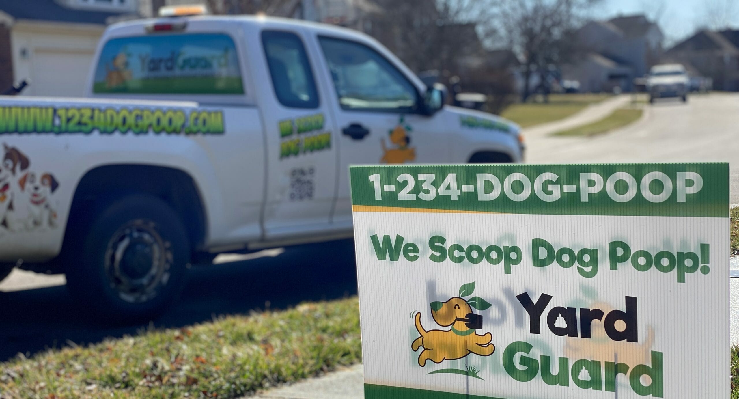 Yard Guard LLC promotional sign and branded truck for dog waste removal service. The sign displays the slogan 'We Scoop Dog Poop!' along with contact information, in a residential neighborhood setting.